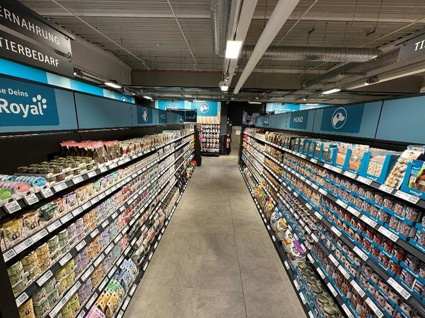 Shop in Shop Zwei Ansichten eines gut sortierten Tierfutter‑Gangs im ZooRoyal‑Markt, mit voll bestückten Regalen und Markenhinweisen.