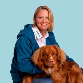Agnes Schwürz Person in ZooRoyal‑Hoodie min einem Hund vor einfarbigem Hintergrund.