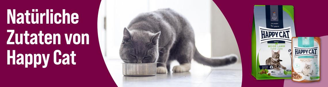 Entdecke Katzenfutter von Happy Cat Aktionsbanner für Katzenfutter von Happy Cat. Katze frisst aus einem Napf in einer Wohnung, daneben Verpackungen von Trocken‑ und Nassfutter, Hinweis auf „Natürliche Zutaten von Happy Cat“.