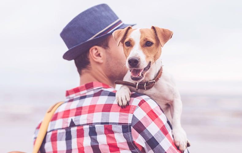 Happy Dog Mini Mann mit Hut hat einen kleinen Hund auf dem Arm.