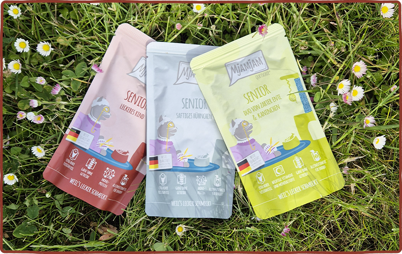 MjAMjAM Senior Drei Pouches Senior Katzenfutter liegen auf einer Wiese.