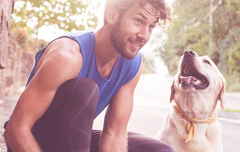 Happy Dog Fit & Vital Hund liegt neben einem Mann auf dem Boden, der sich dehnt.